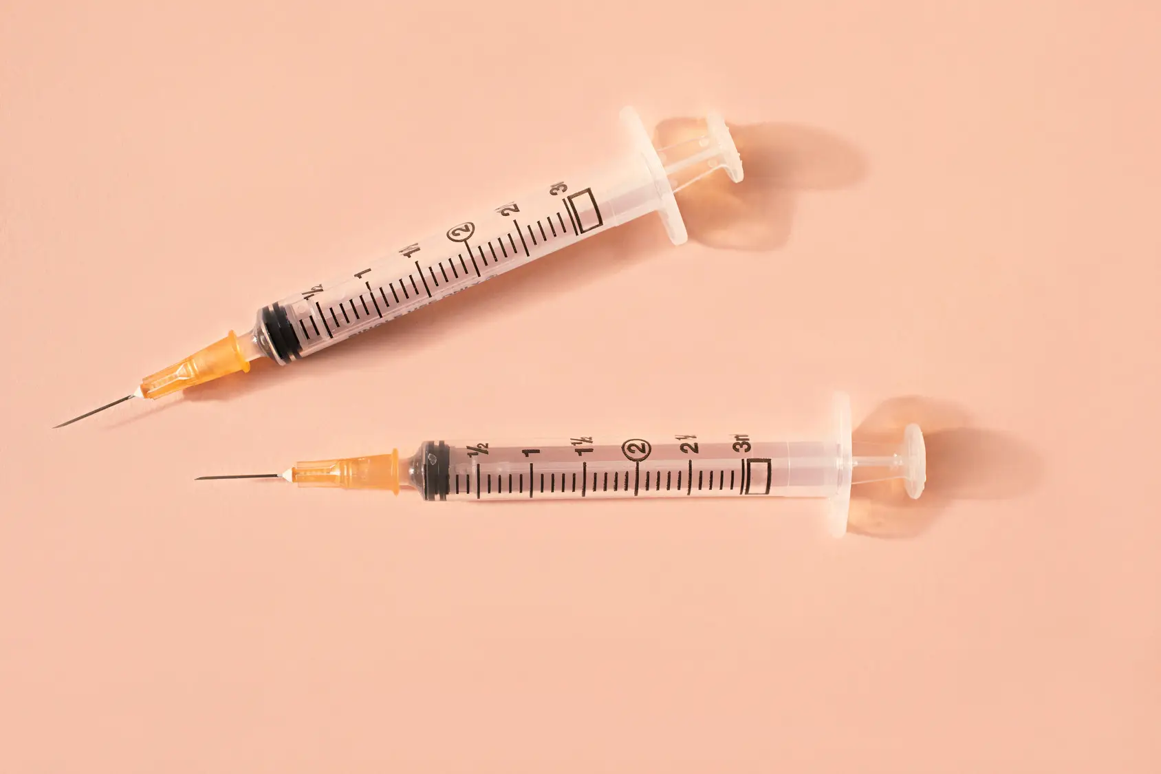 close up of syringes and sharp needles on pink background
